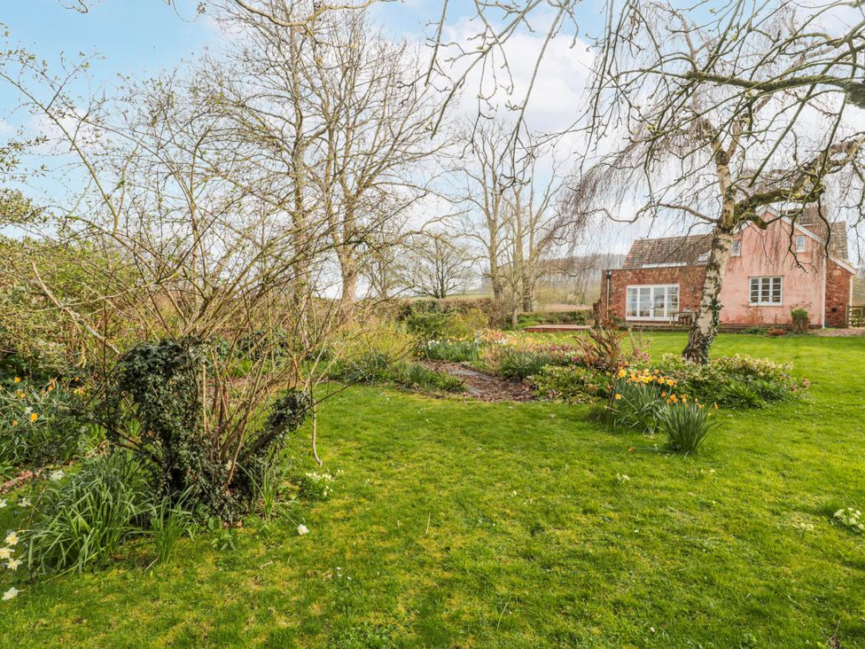 A garden with trees, bushes, flowers and a house at Tuxwell Lodge near Nether Stowey
