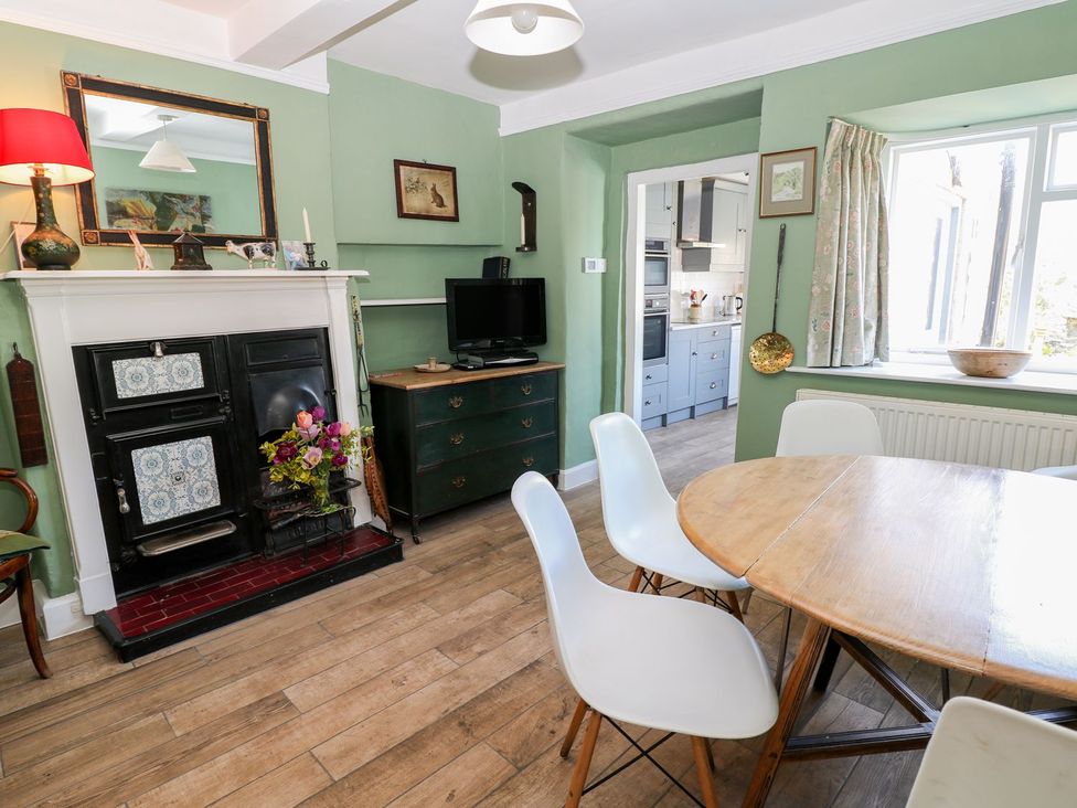 A dining room with a fireplace and a table at Ivy Cottage in Hartington