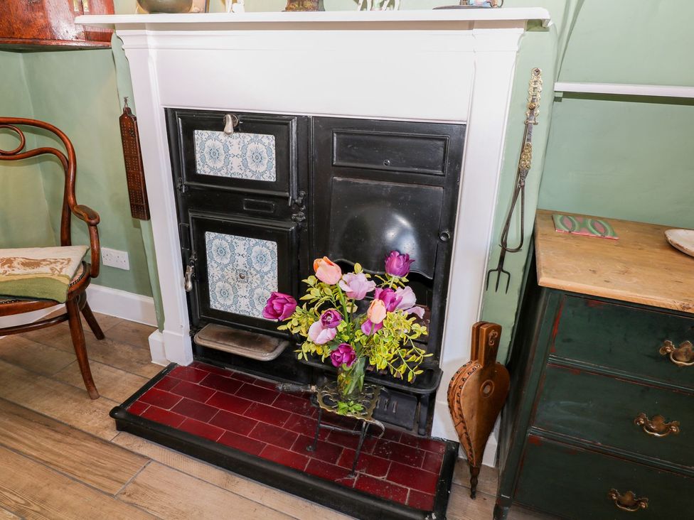 A fireplace with a flower vase in front at Ivy Cottage in Hartington