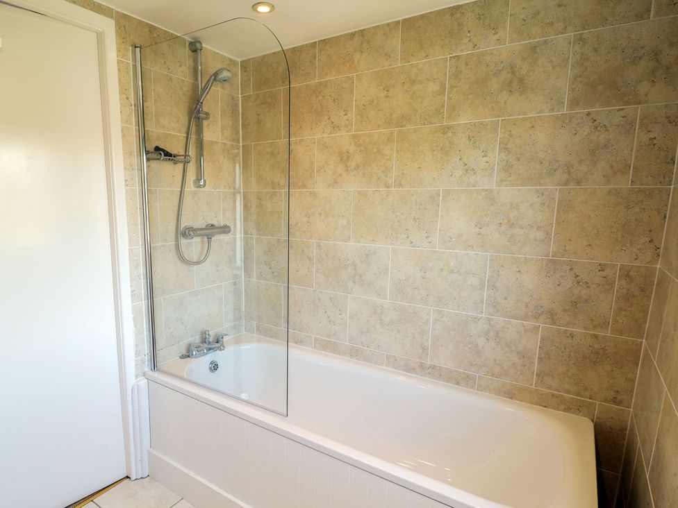 A bathtub with shower in a bathroom at Ivy Cottage in Hartington