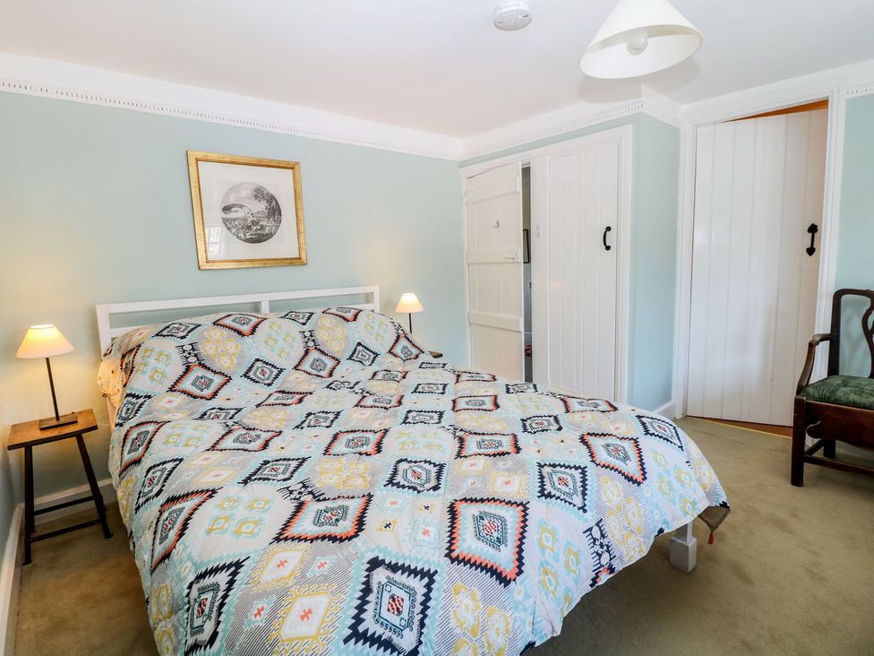 A bedroom with a bed, lamps, and a chair at Ivy Cottage in Hartington