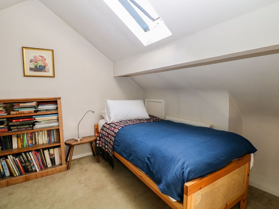A bedroom with a bed, bookshelf, and lamp at Ivy Cottage in Hartington