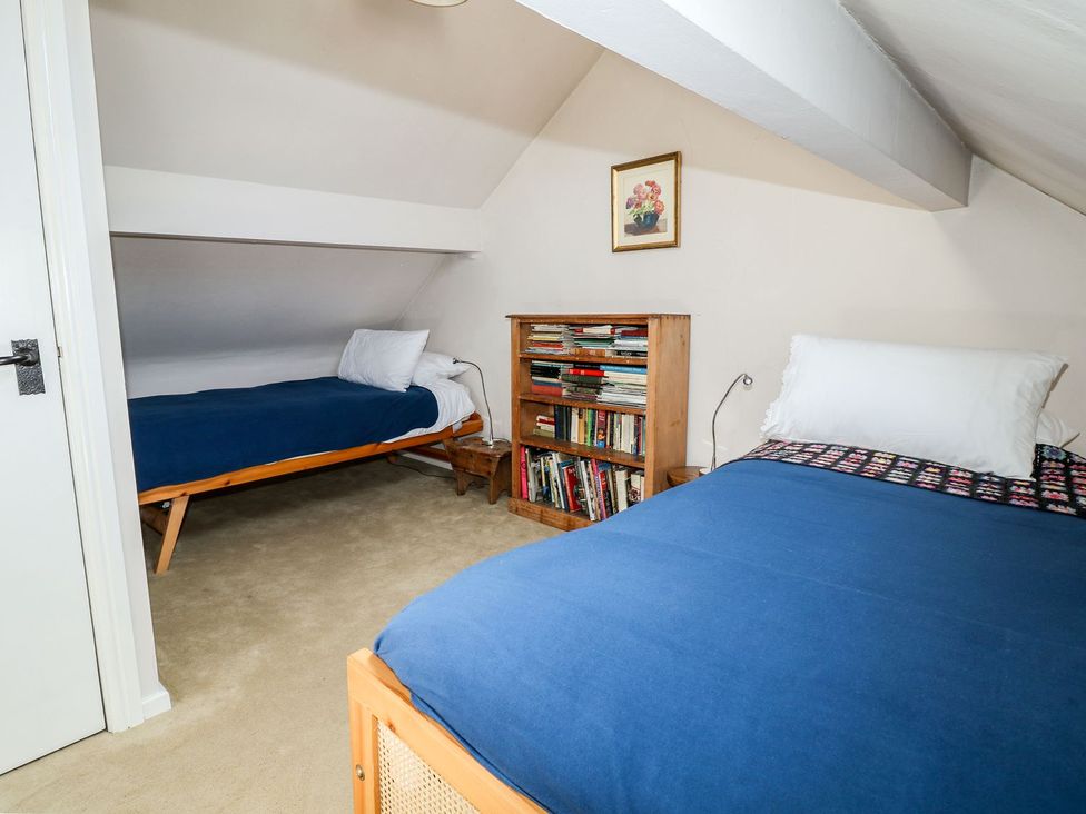A bedroom with two beds and a bookshelf at Ivy Cottage in Hartington