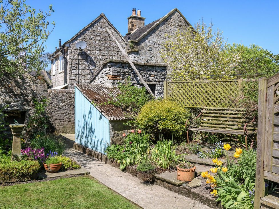 A garden with flowers and a bench at Ivy Cottage in Hartington