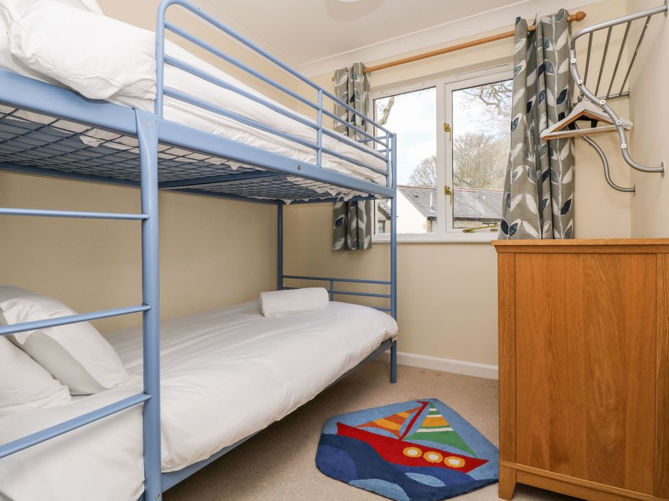 A bedroom with a bunk bed and a wooden cabinet at Oak Cottage in Falmouth