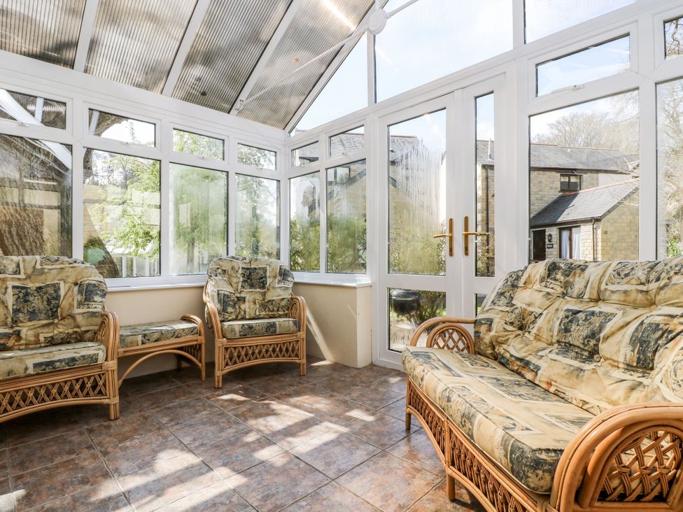 A conservatory with seating and windows at Oak Cottage in Falmouth