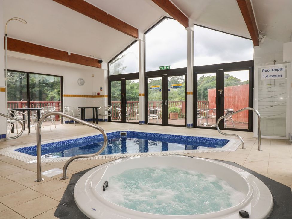 An indoor pool area with a hot tub and swimming pool at Oak Cottage in Falmouth