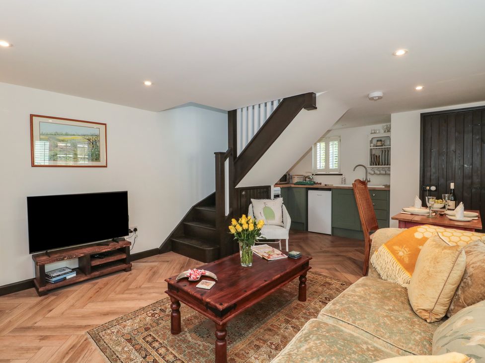 A living room featuring a sofa, coffee table, and a television at Ruby’s Den in Ashton Keynes