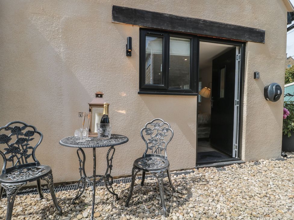 An outdoor seating area with a table, chairs, and drinks at Ruby’s Den in Ashton Keynes