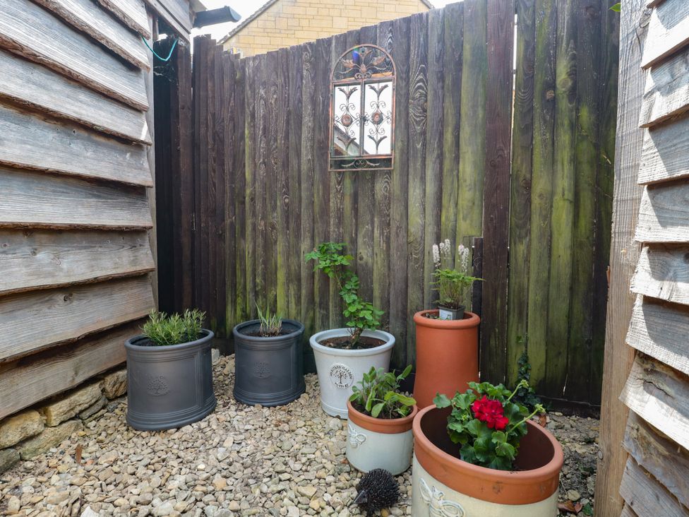 A garden with potted plants and a wooden fence at Ruby’s Den Ashton Keynes