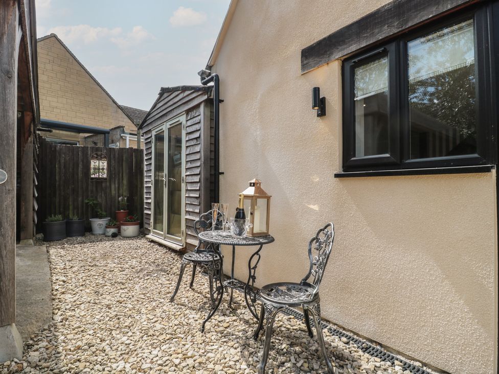 A garden with a small table and chairs beside a fence at Ruby’s Den Ashton Keynes