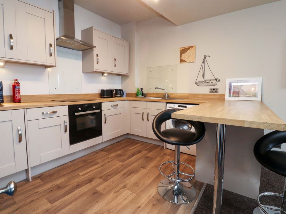 A kitchen with cabinets, a sink, oven, and bar stools at Flat 2, Dorstan in Carnforth
