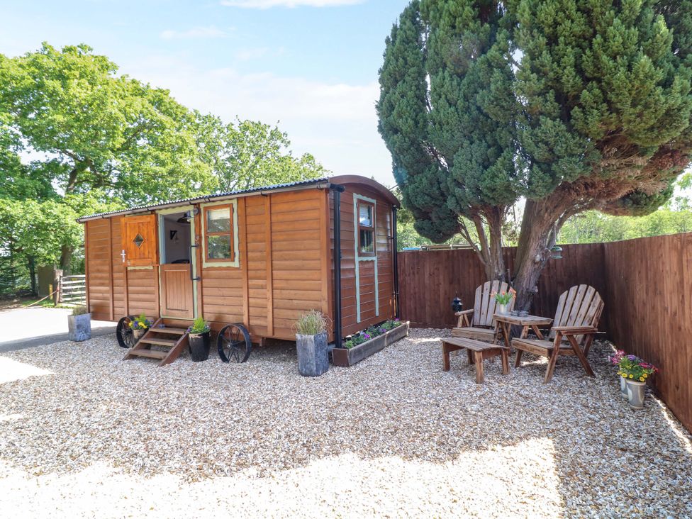 An outdoor area with a shed, chairs and table at Shepherds Hut in South Hykeham
