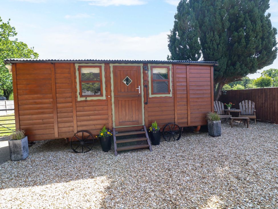 An outdoor view of a shepherd hut with steps and chairs at Shepherds Hut in South Hykeham