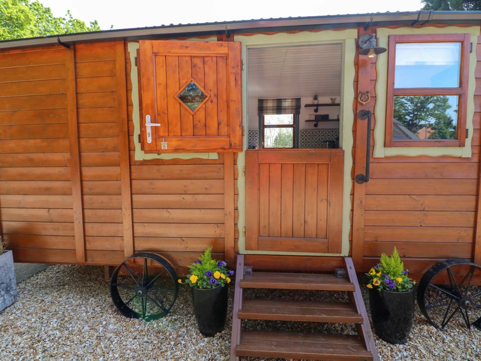 An entrance to a wooden hut with steps and planters at Shepherds Hut in South Hykeham