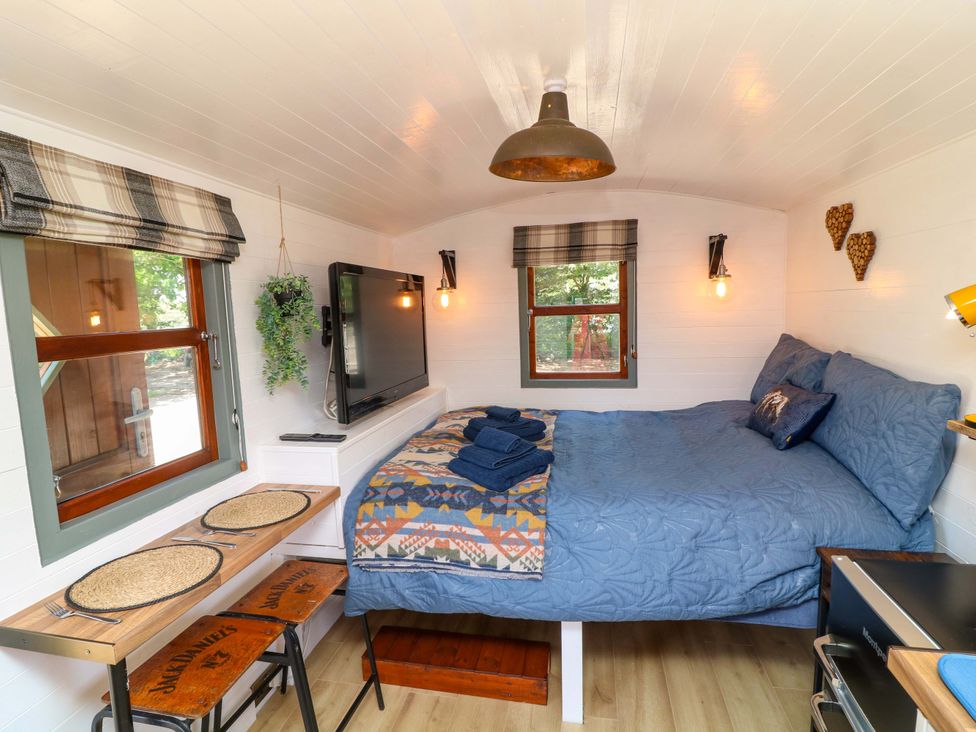 A bedroom with a bed and television at Shepherds Hut in South Hykeham