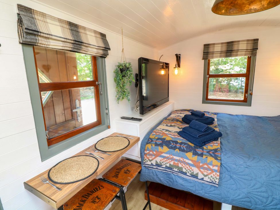 A sleeping area with a bed and table at Shepherds Hut in South Hykeham