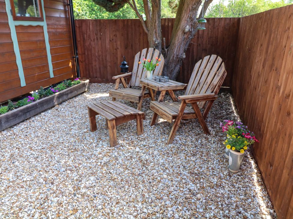 A garden seating area with wooden chairs and a table at Shepherds Hut in South Hykeham