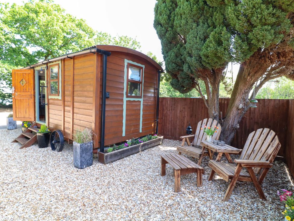 An outdoor area with a shepherd hut and seating at Shepherds Hut in South Hykeham