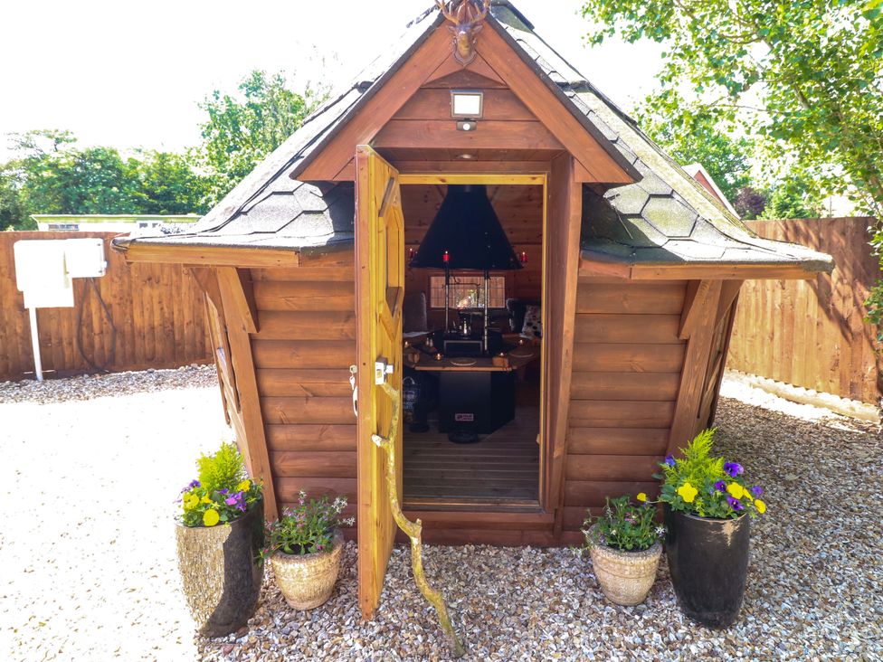 A wooden structure with an open door and gravel surrounds at Shepherds Hut in South Hykeham