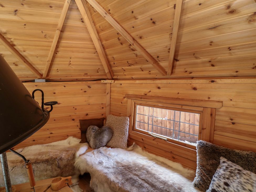 An indoor seating area with wooden walls and a window at Shepherds Hut in South Hykeham