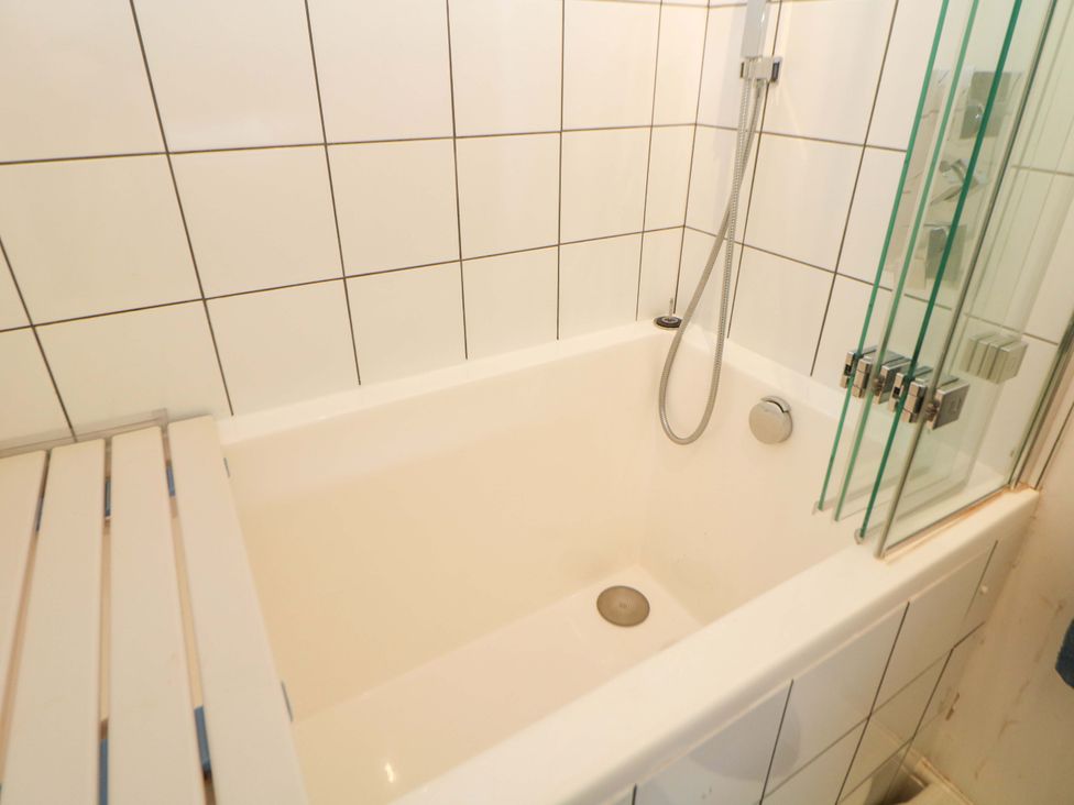 A bathtub with a showerhead in a bathroom at Glenside Lodge Chapel-En-Le-Frith