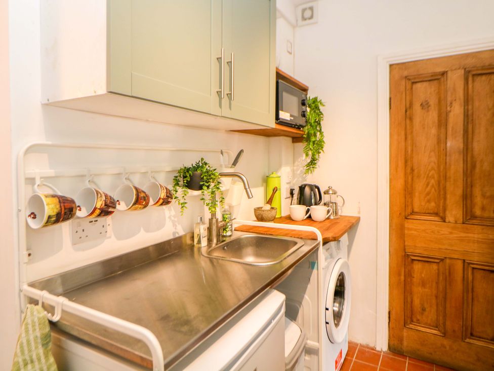 A kitchen with sink, cabinet, microwave, kettle, and washing machine at Glenside Lodge, Chapel-En-Le-Frith