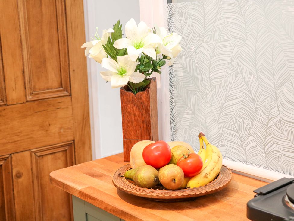 A kitchen counter with a vase of flowers and a bowl of fruits at Glenside Lodge in Chapel-En-Le-Frith