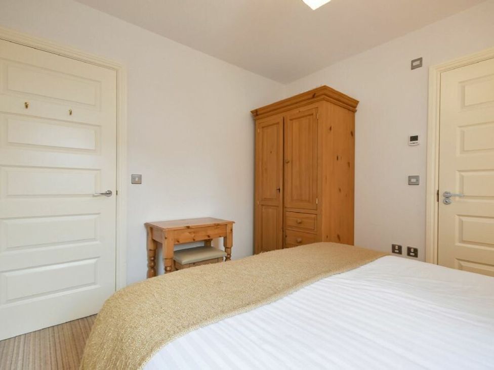 A bedroom with a bed, wardrobe, and table at Northrawe in Bamburgh