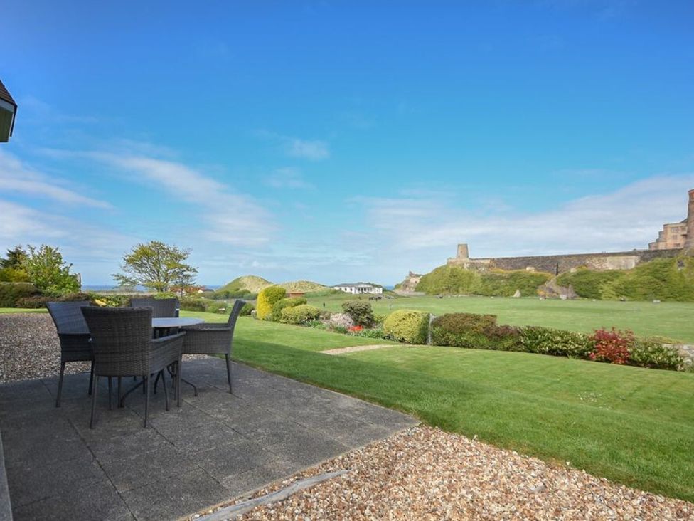 A garden with furniture facing a castle at Northrawe in Bamburgh