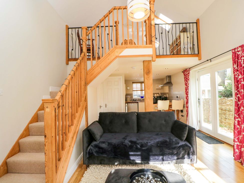 A living room with a staircase and kitchen area at The Barn at Myrtle Cottage
