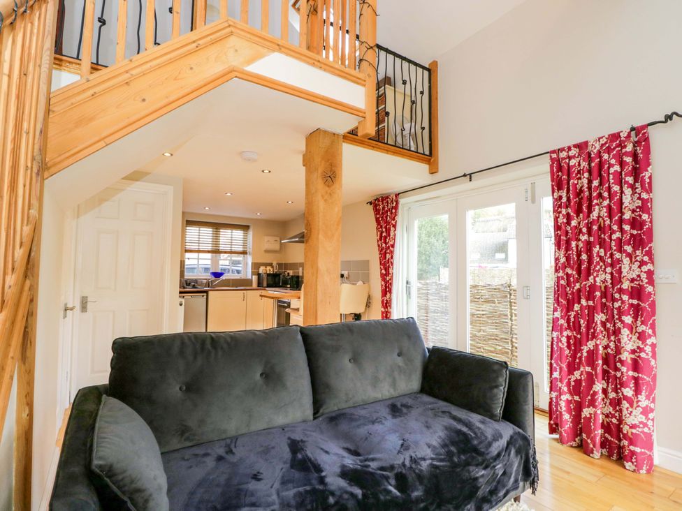 A living room with a staircase and kitchen area at The Barn at Myrtle Cottage