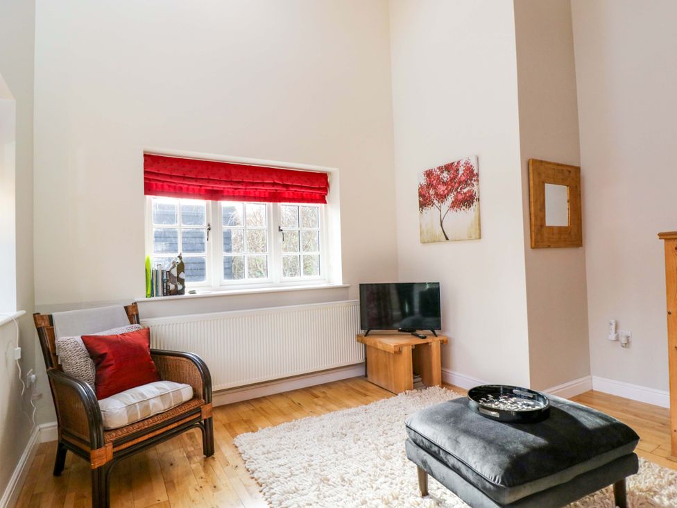 A living room with a chair, table, and television at The Barn at Myrtle Cottage