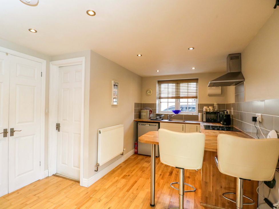 A kitchen with bar stools and appliances at The Barn at Myrtle Cottage