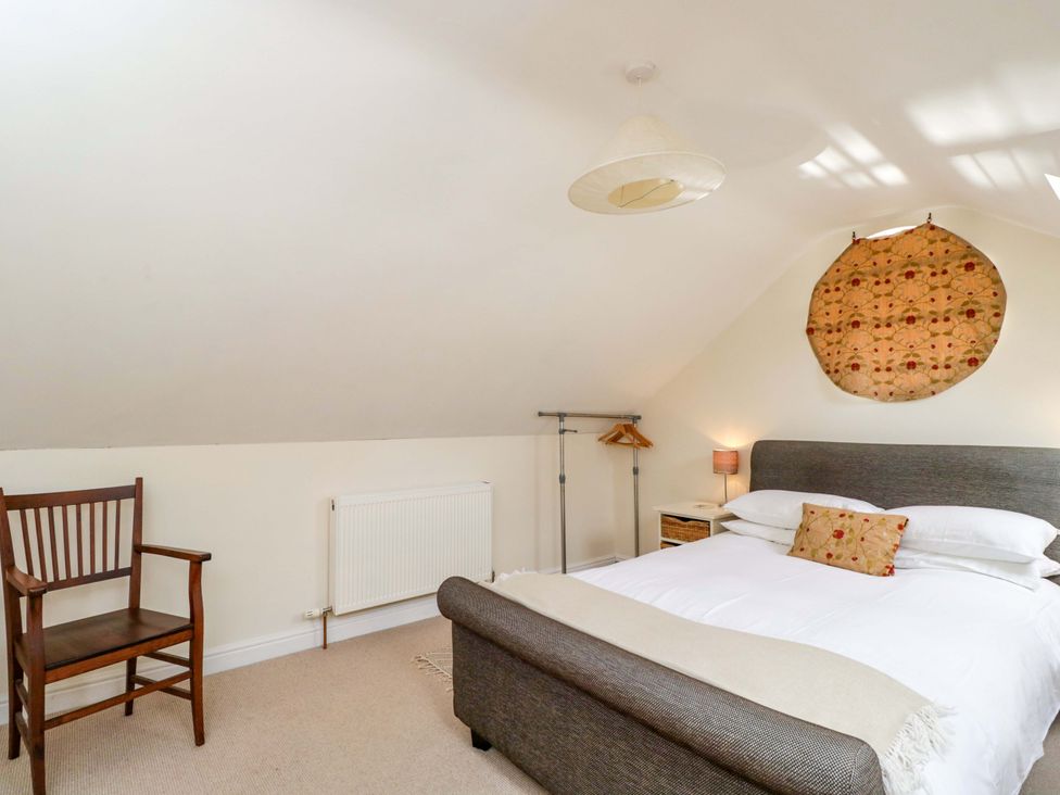 A bedroom with a bed, chair, and lamp at The Barn at Myrtle Cottage