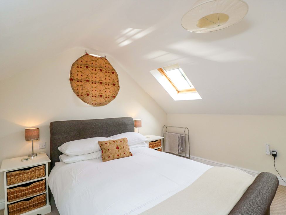 A bedroom with a bed, bedside tables, and a skylight at The Barn at Myrtle Cottage