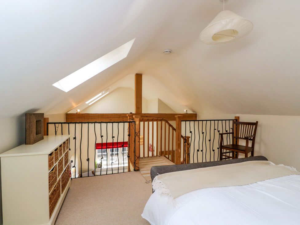 A loft with bed, chair and shelves at The Barn at Myrtle Cottage