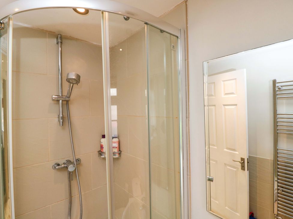 A shower enclosure with a towel rack and mirror at The Barn at Myrtle Cottage