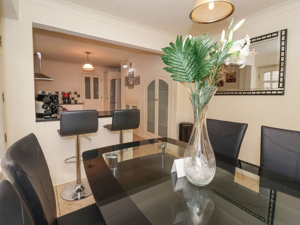 A dining room with a glass table and kitchen view at Blacksmiths Mews in York