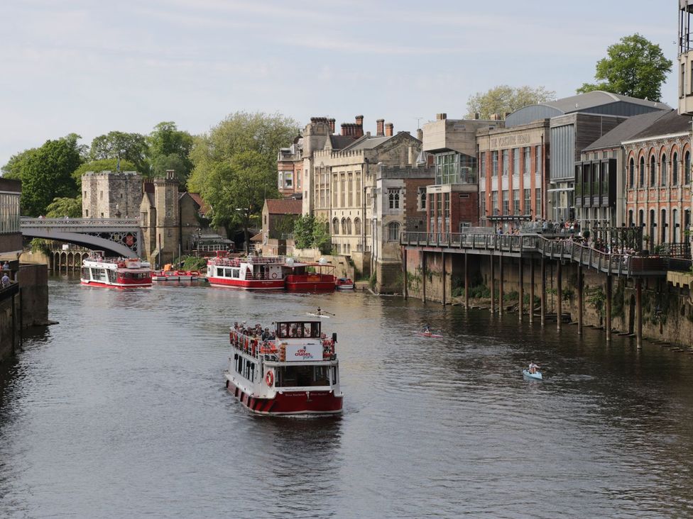 A river with boats and buildings along the banks at Blacksmiths Mews in York