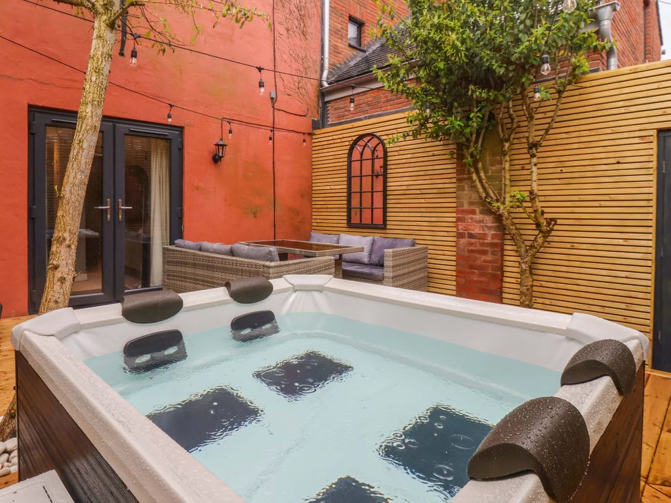 An outdoor area with a hot tub and seating at Blacksmiths Retreat, York
