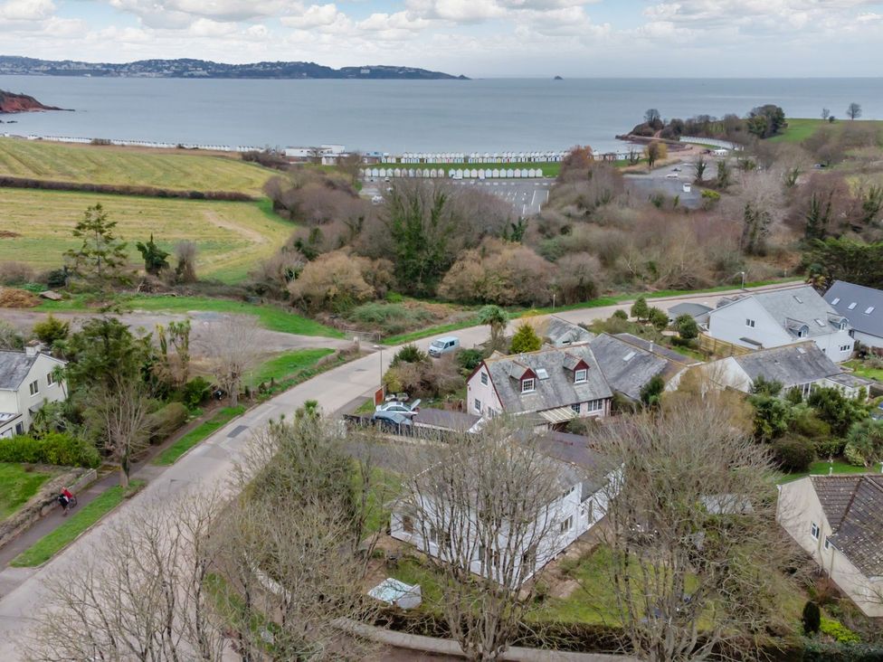 An aerial view of a coastal area with houses and beach huts at Broadsands in Paignton