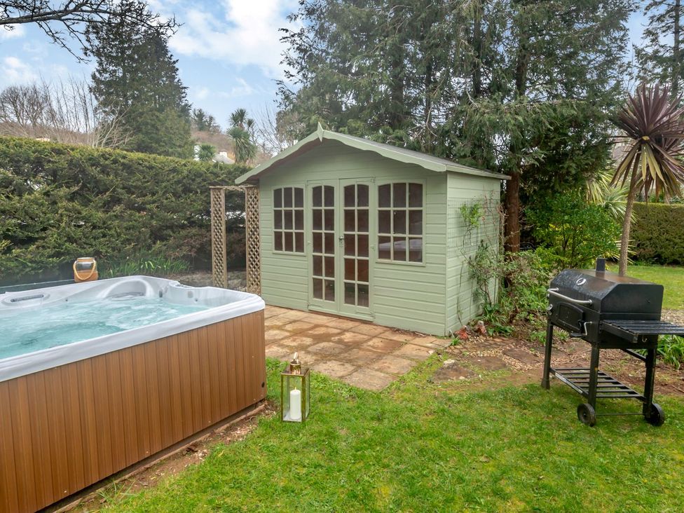 A garden with a hot tub, a shed, and a barbecue grill at Broadsands in Paignton