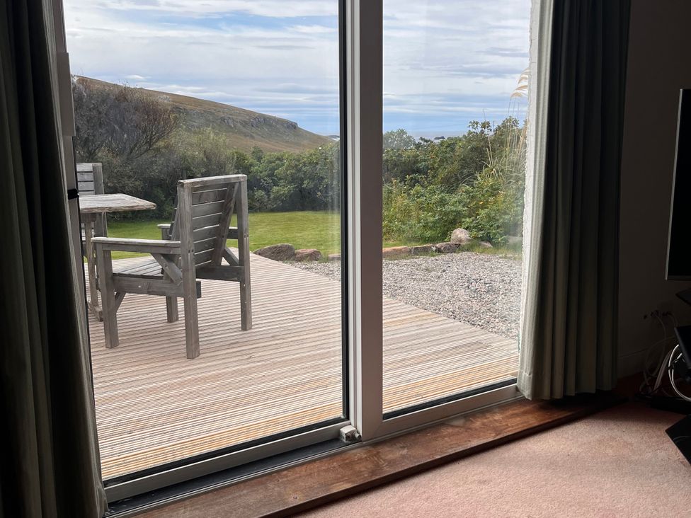 A living room with a sliding door leading to a deck and garden at An Grianan in Lairg