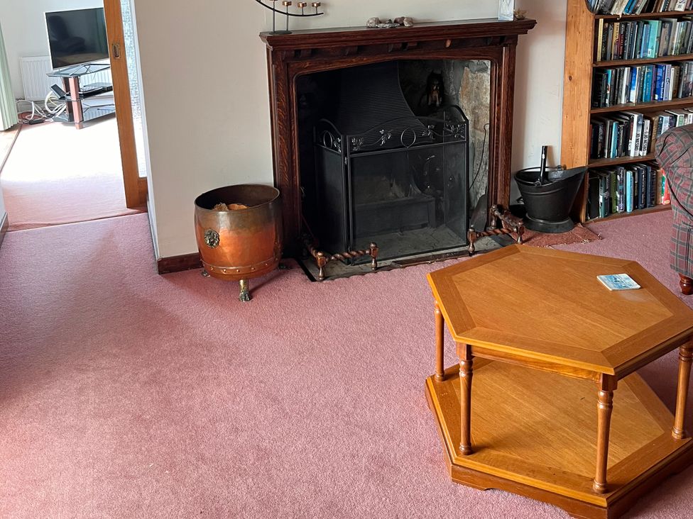 A living room with a fireplace and a wooden table at An Grianan in Lairg