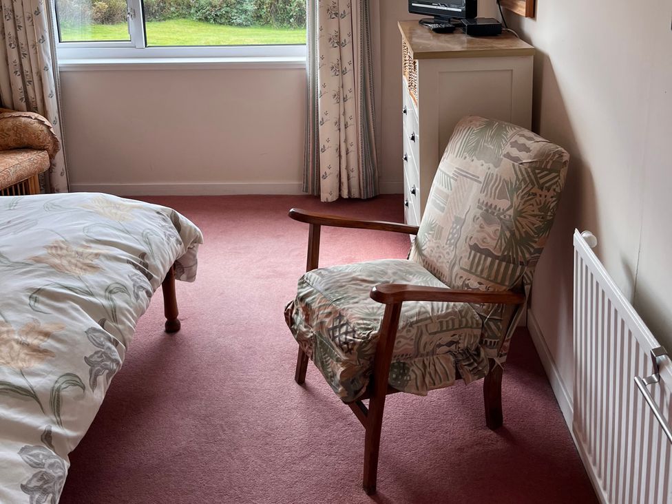 A bedroom with a bed and chair at An Grianan, Lairg