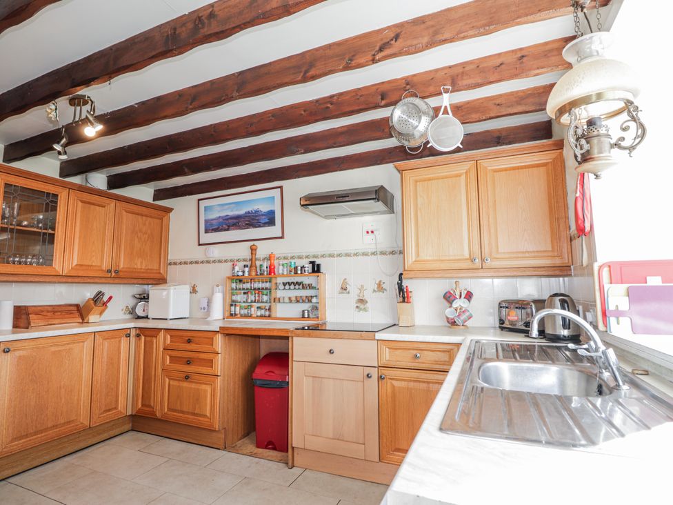 A kitchen with wooden cabinets and appliances at An Grianan Kinlochbervie