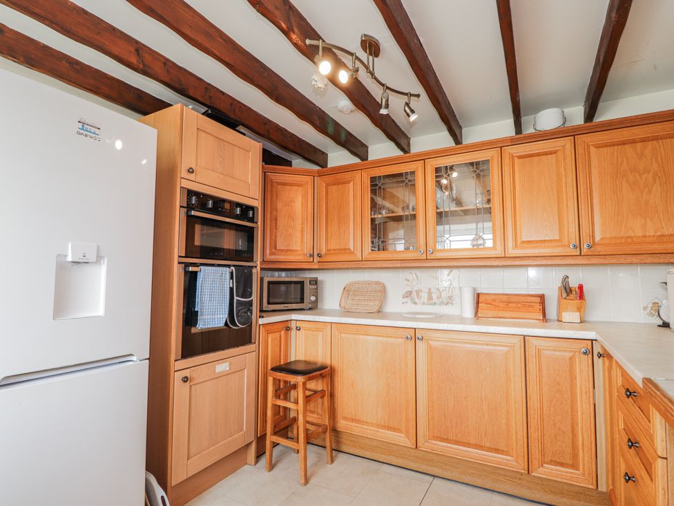 A kitchen with wooden cabinets and appliances at An Grianan in Kinlochbervie