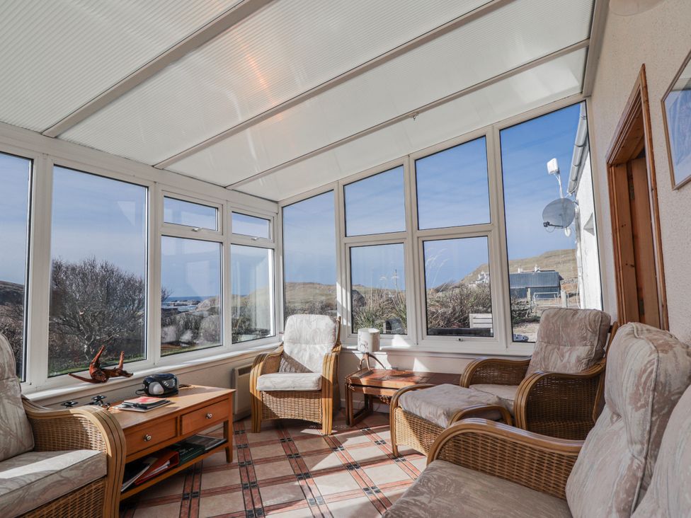 A conservatory with chairs and a table at An Grianan in Kinlochbervie