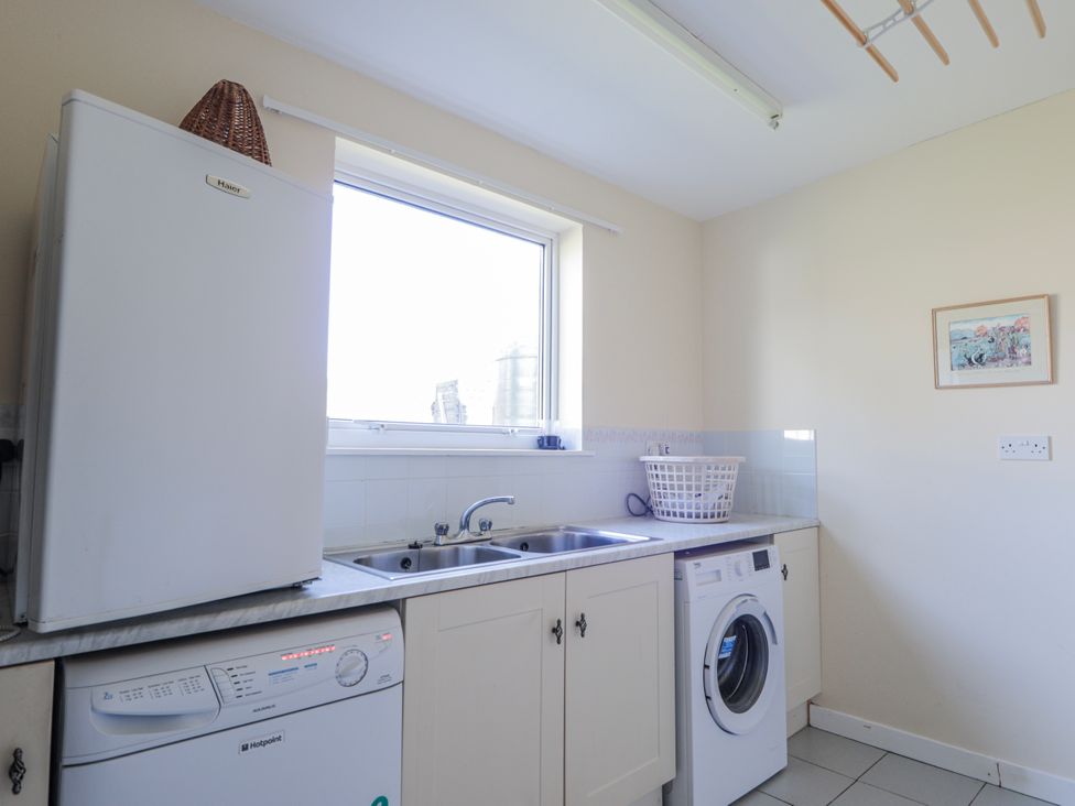 A laundry room with a refrigerator and a washing machine at An Grianan in Kinlochbervie